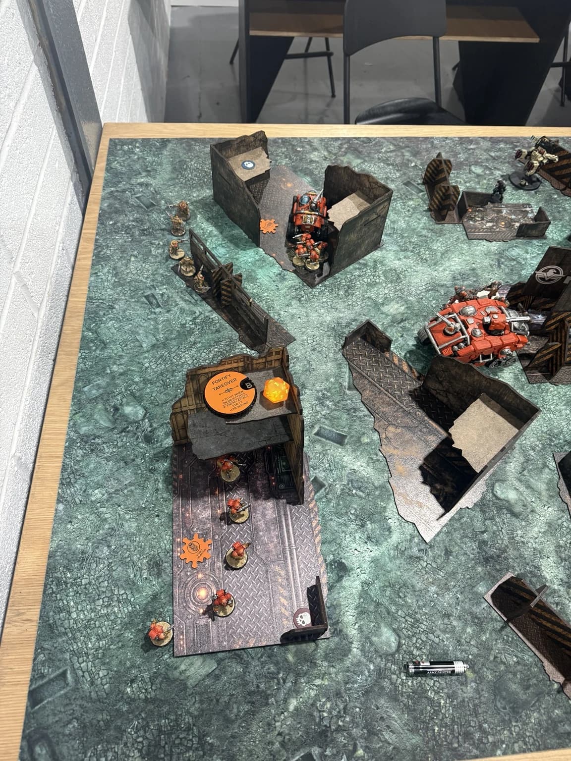 Close photograph of orange infantry spread around the rear terrain and a Sagitaur inside a nearby ruin